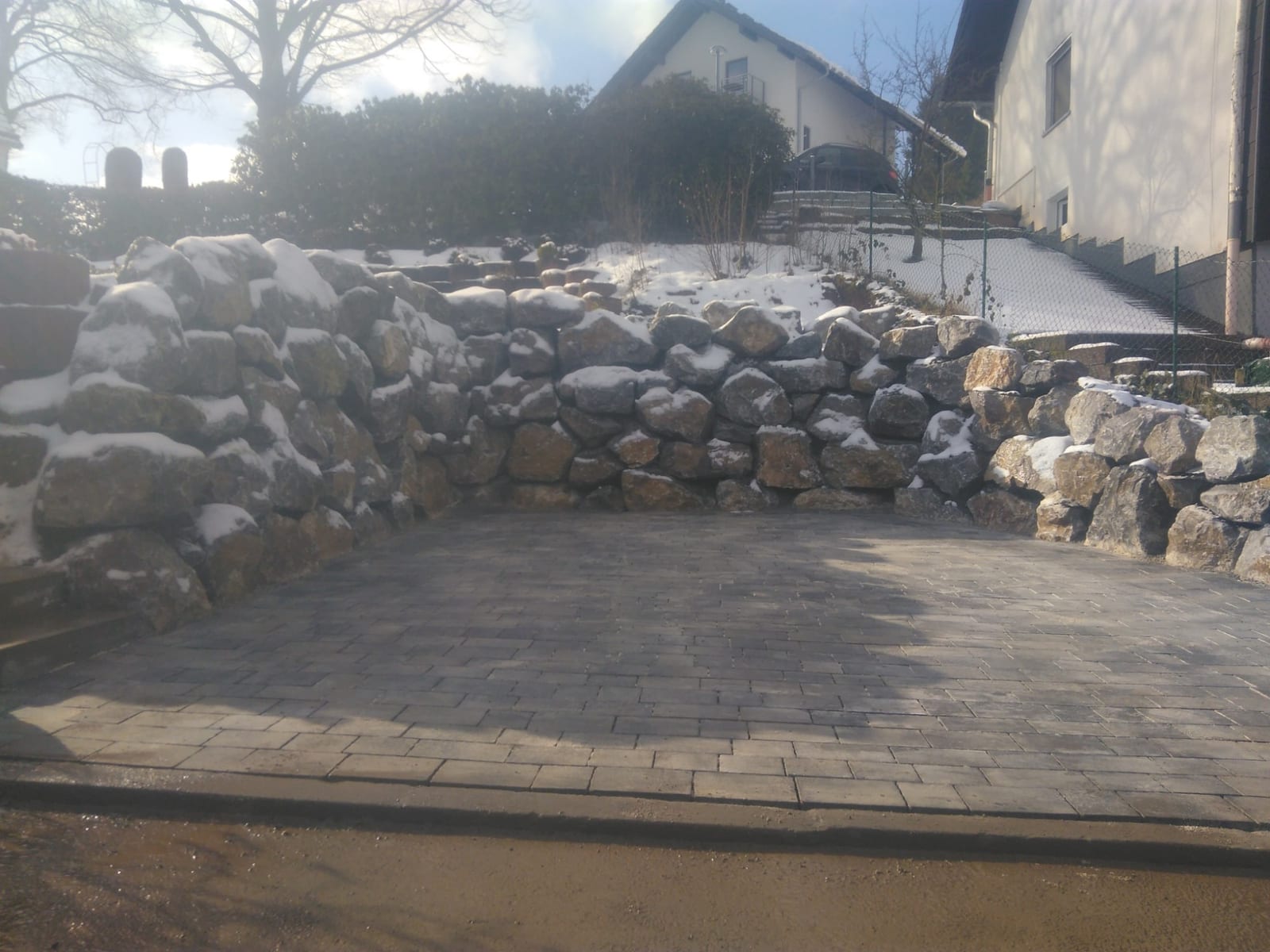 Fertig gepflasterte Stellfläche mit Natursteinabfangung